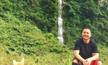 Happy trekker in front of small waterfall