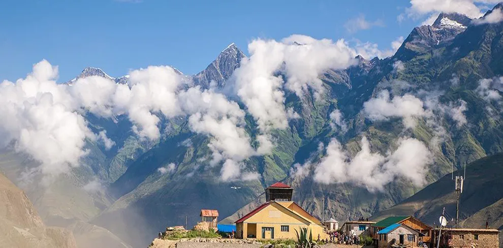 The houses of Juphal stand against a backdrop of rolling landscapes and mountains shrouded in clouds