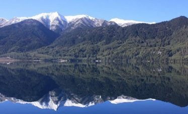 reflection of snow capped mountains on the blue water of Rara lake