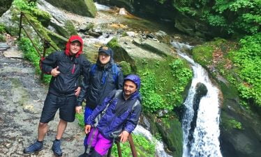 Boys pose at waterfall site in the rain