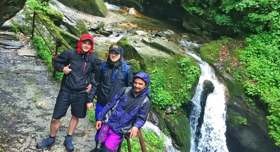 Boys pose at waterfall site in the rain