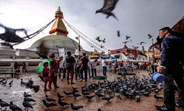 Boudhanath stupa and a man feeding birds at kathmandu