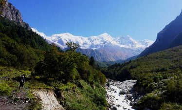 River coming from Bhimtang village and trekkers staring at the white mountains