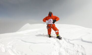 Climbing guide with flag of Nepalgram at the summit