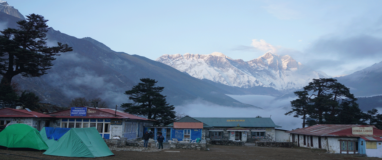 Rekking village near gokyo lake, nepal, with tents and lodges beneath snow-covered himalayan peaks and morning mist.