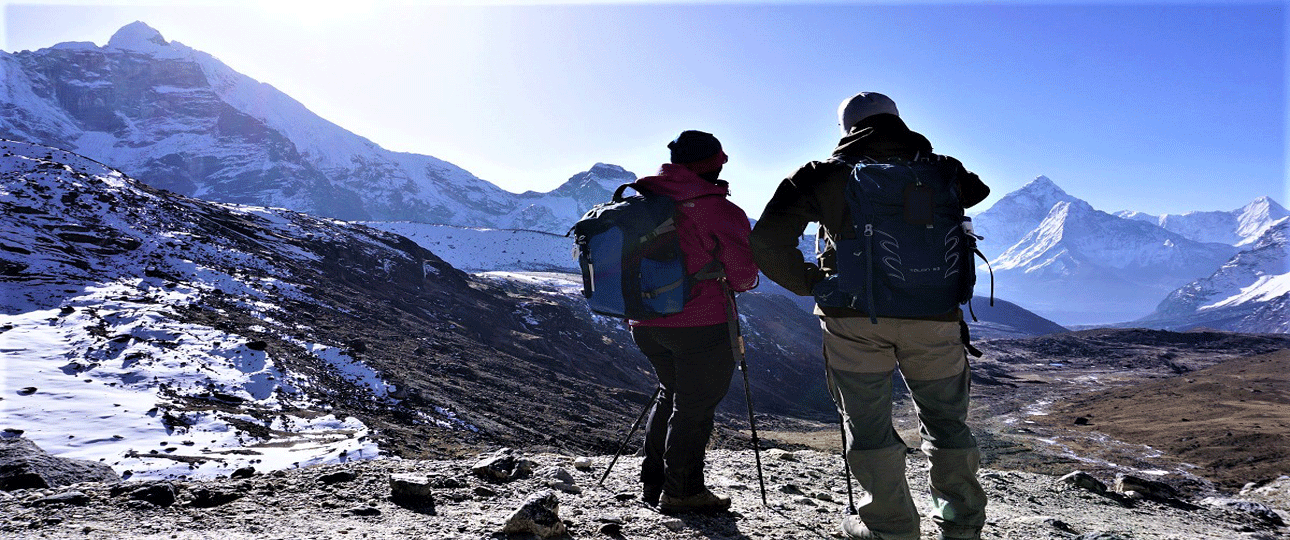 Trekkers enjoying a mountain viewpoint on the gokyo lake trek with snow-covered himalayan peaks.